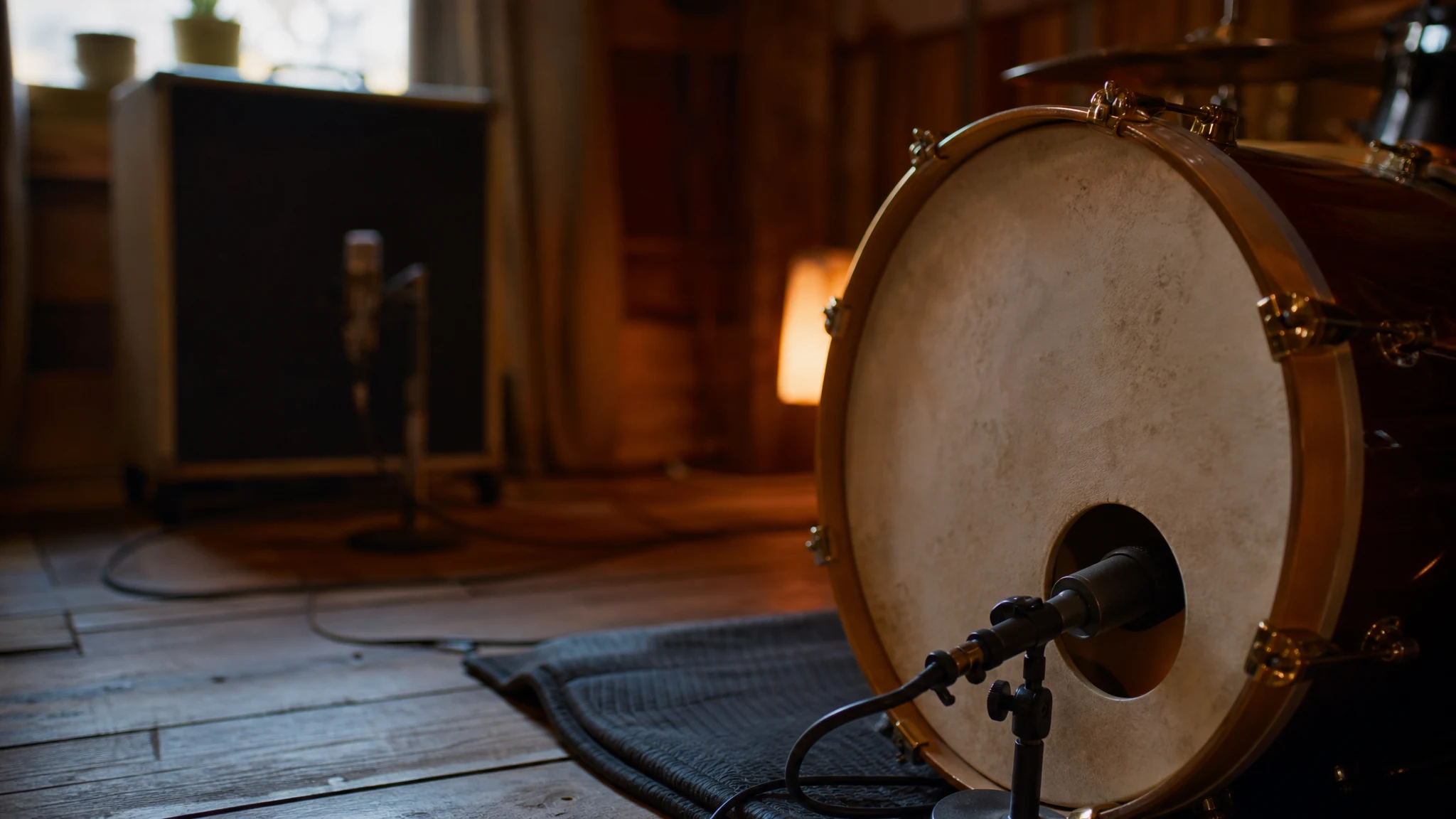 Kick drum with a microphone at the port hole and a bass cabinet behind it in a live room